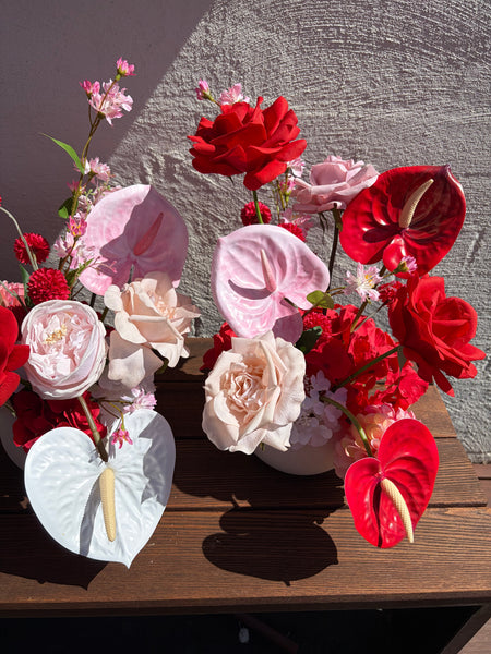 Colourful flower arrangement of pink and orange flowers on a wooden bench
