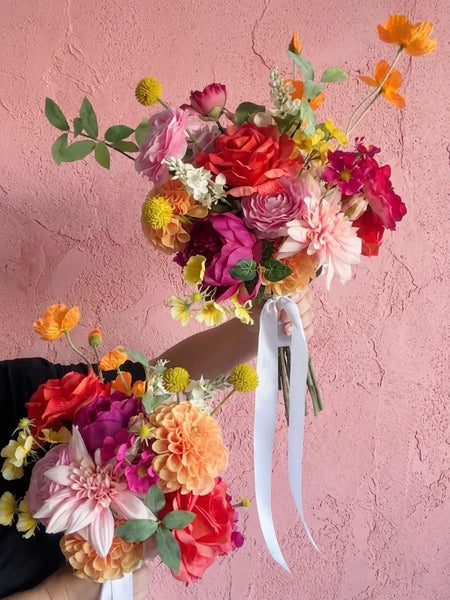 Two vibrant artificial wedding bouquets with a textured pink wall in the background
