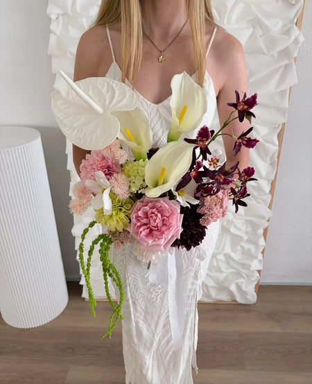 Lady in a white dress holding an artificial wedding bouquet with a sculptural silhouette
