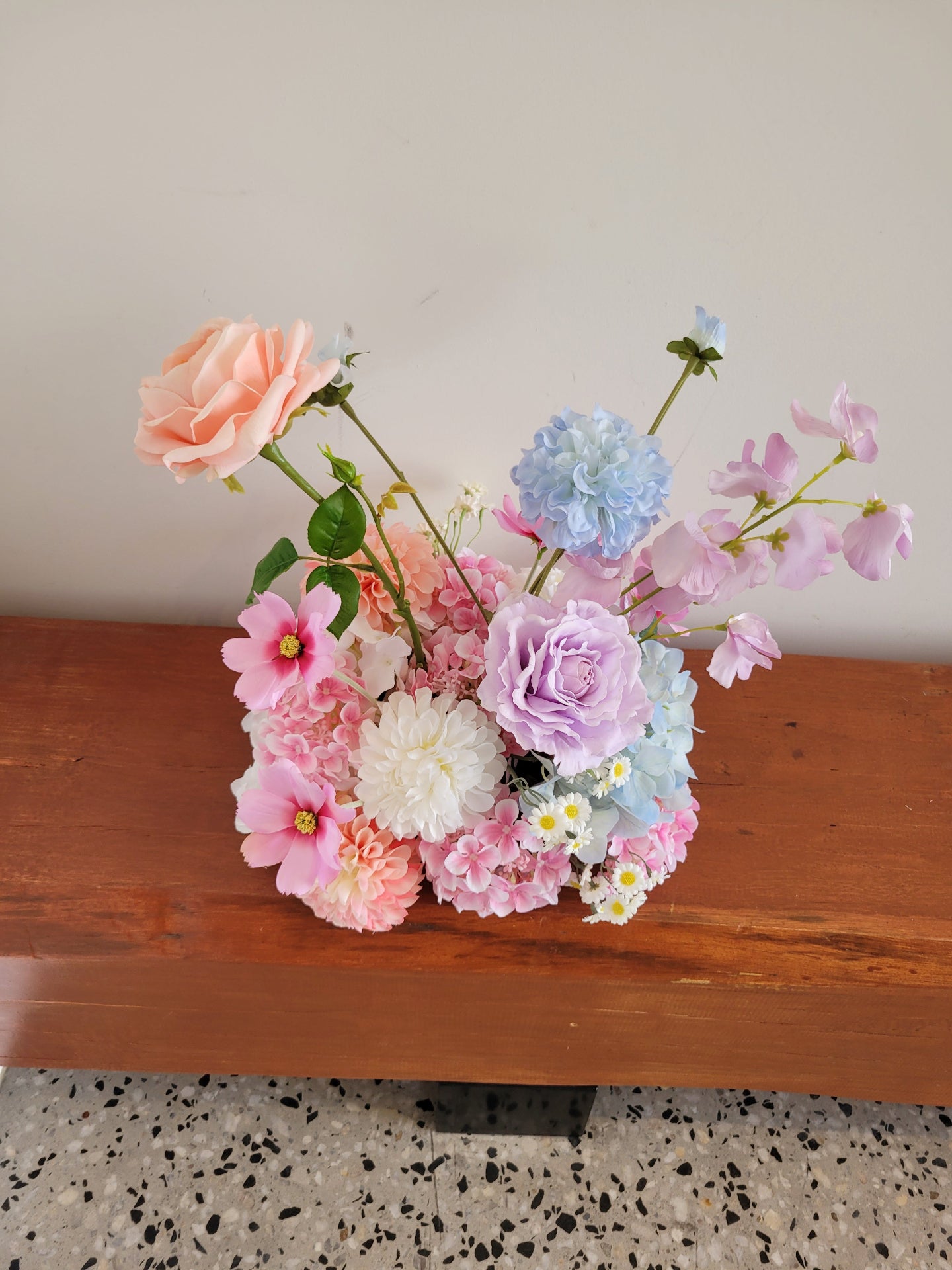 Bouquet of colorful flowers on a wooden surface with a neutral background