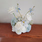 Floral arrangement with white and light blue flowers on a wooden surface