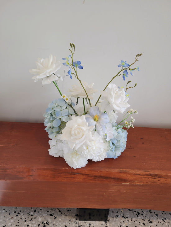 Floral arrangement with white and light blue flowers on a wooden surface