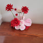 Decorative flower arrangement cloud with red and pink flowers on a wooden surface.