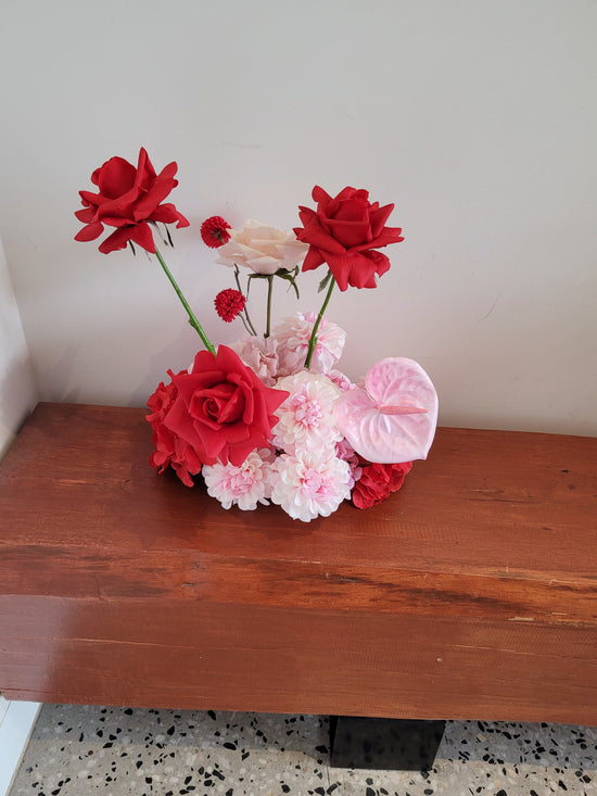 Decorative flower arrangement cloud with red and pink flowers on a wooden surface.