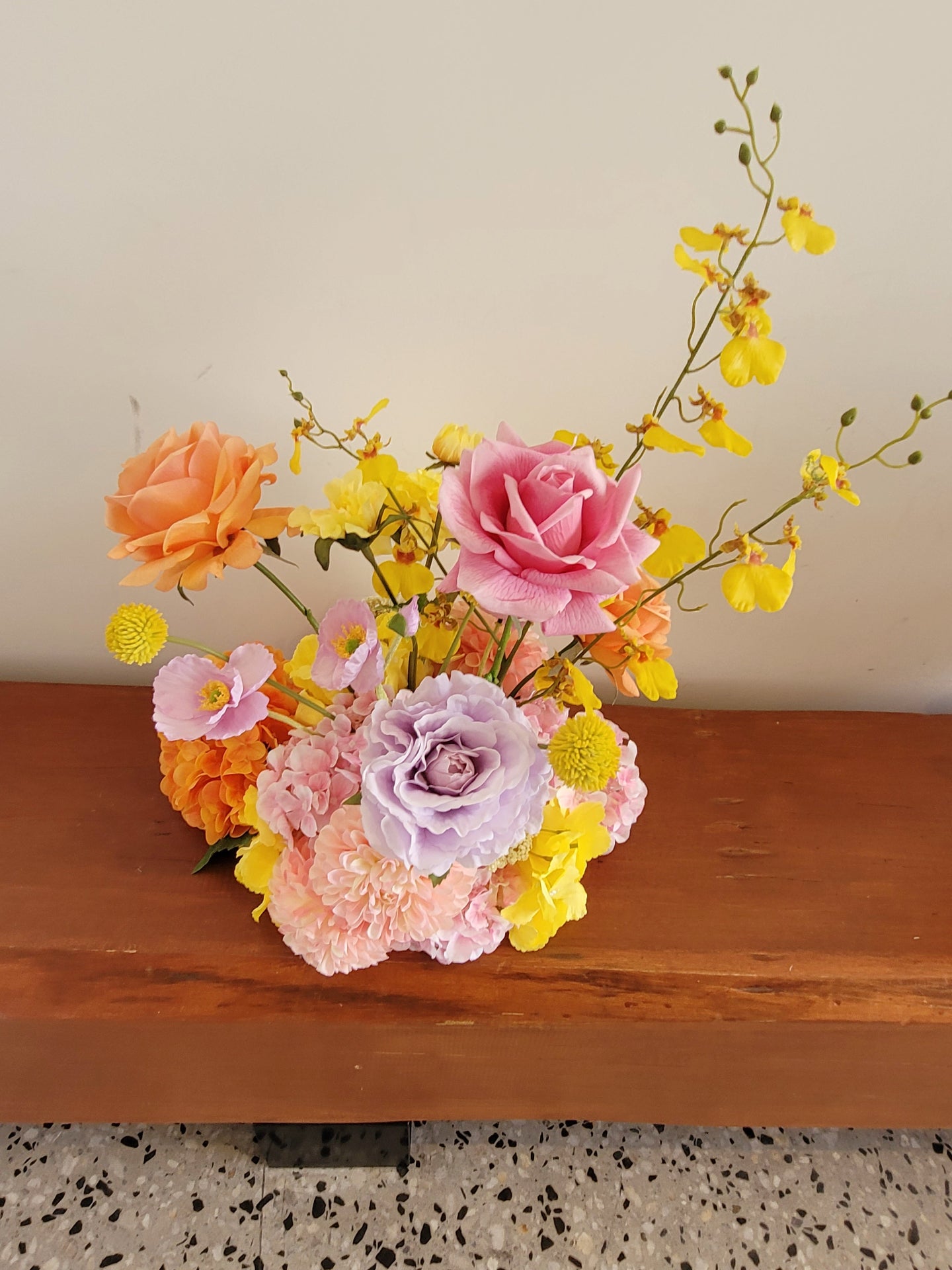 Colorful flower arrangement on a wooden surface with a neutral background