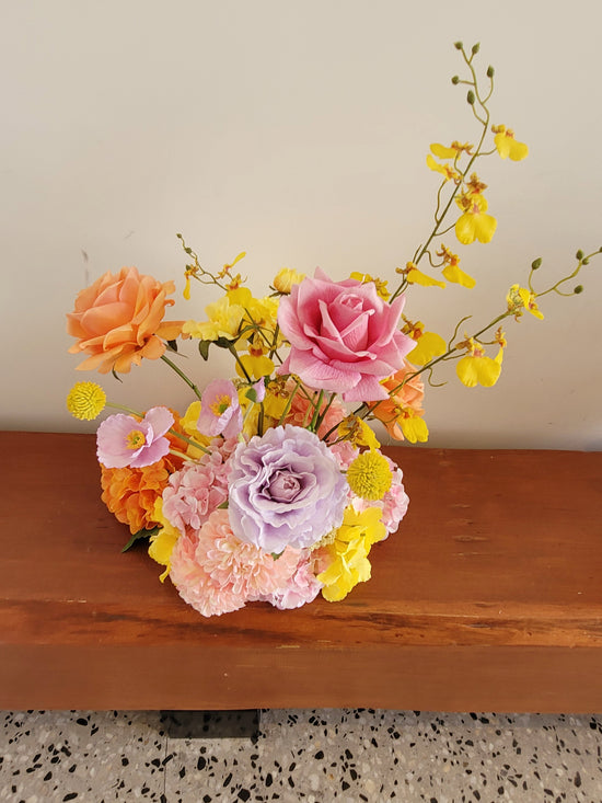 Colorful flower arrangement on a wooden surface with a neutral background