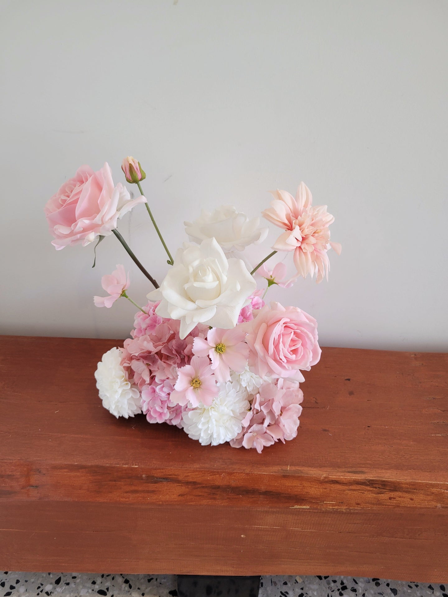 Floral arrangement with pink and white flowers on a wooden surface
