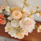Floral arrangement with peach and white flowers on a wooden surface.
