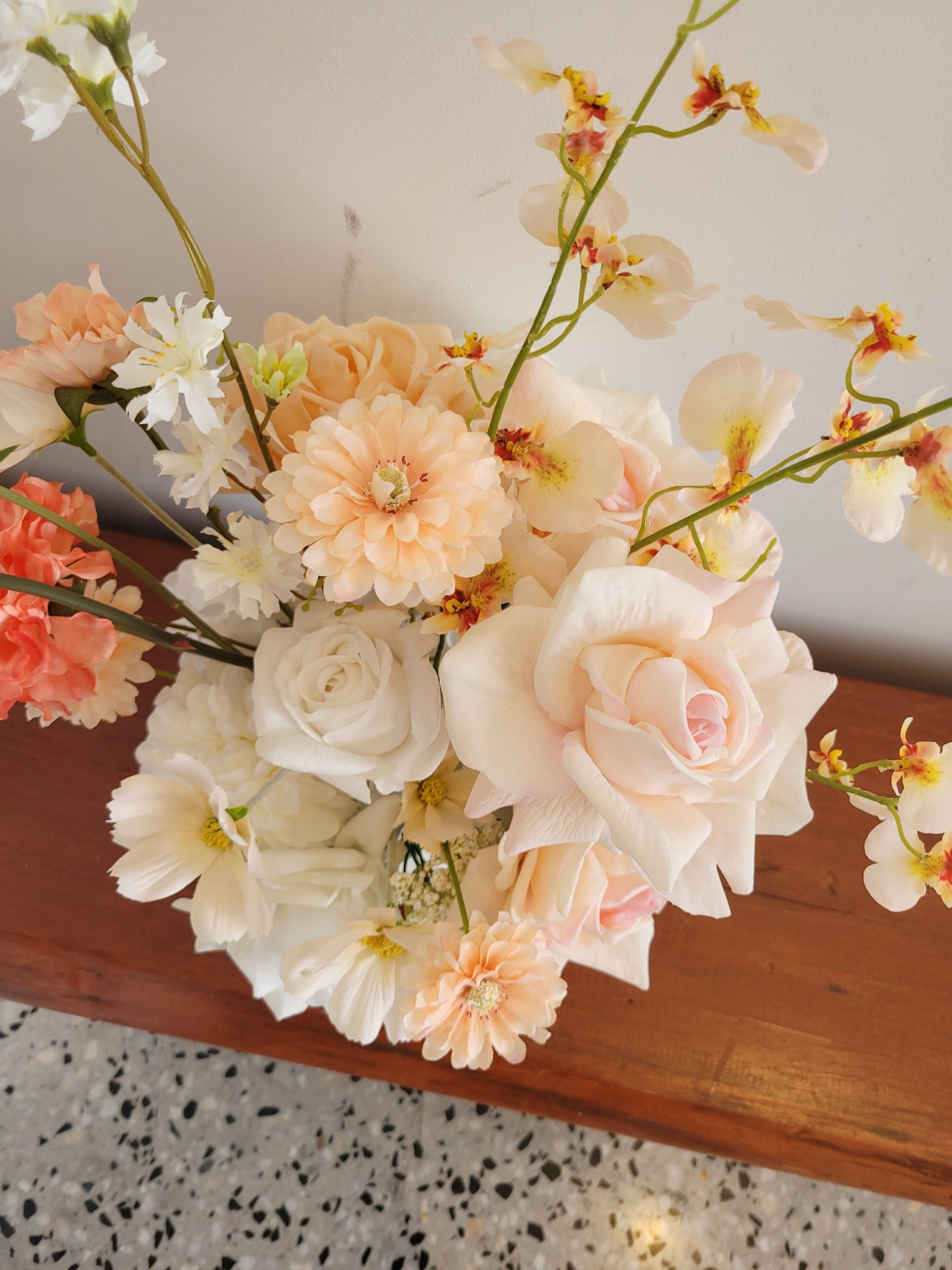 Floral arrangement with peach and white flowers on a wooden surface.