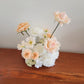 Floral arrangement with peach and white flowers on a wooden surface