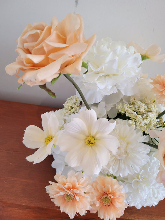 Bouquet of peach and white flowers on a wooden surface