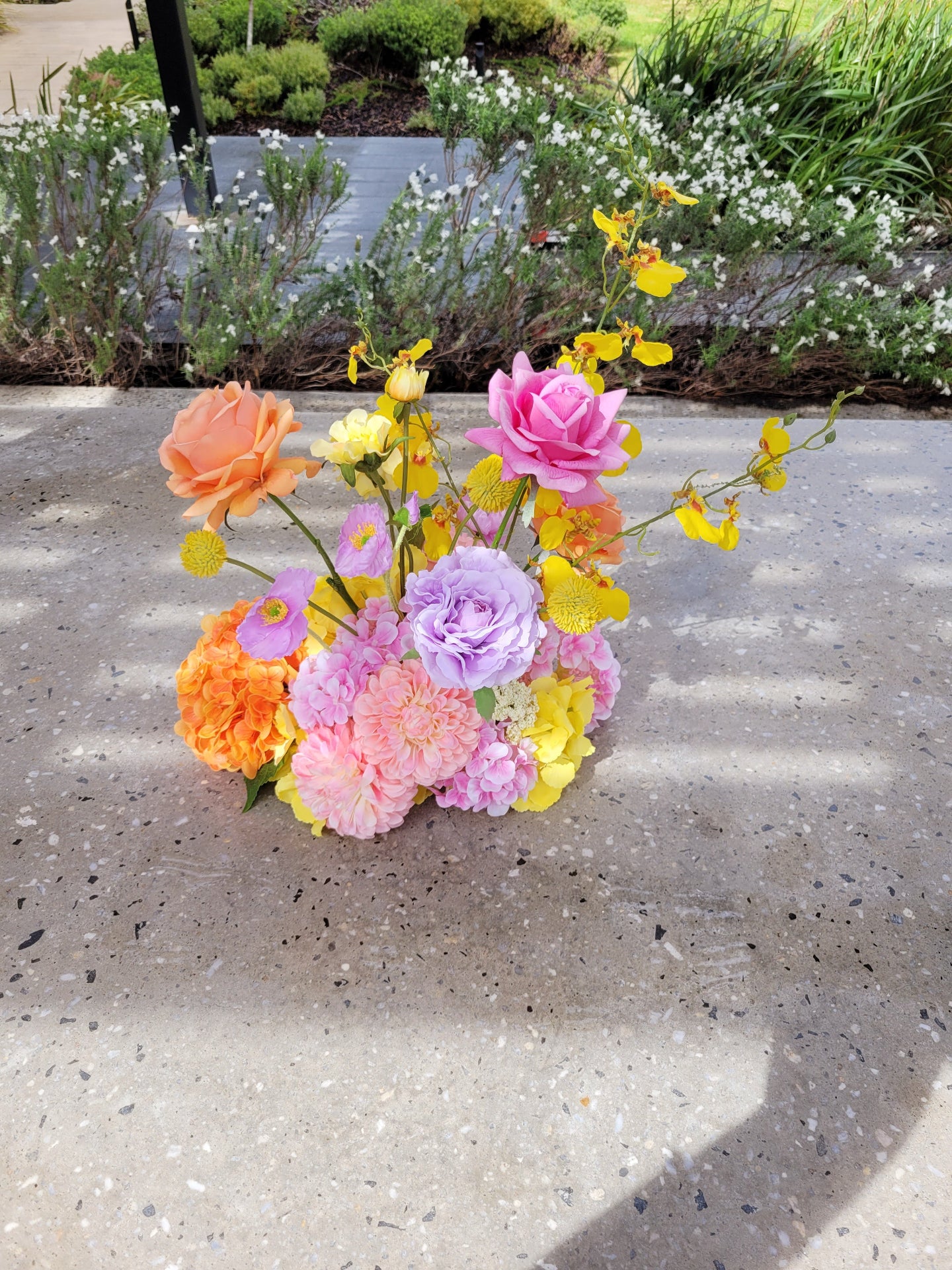 Colorful bouquet of flowers on a concrete surface with greenery in the background
