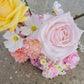 Bouquet of flowers including pink roses, yellow rose, and other assorted flowers on a concrete surface.