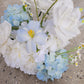 Flower cloud of white and light blue flowers on a concrete surface