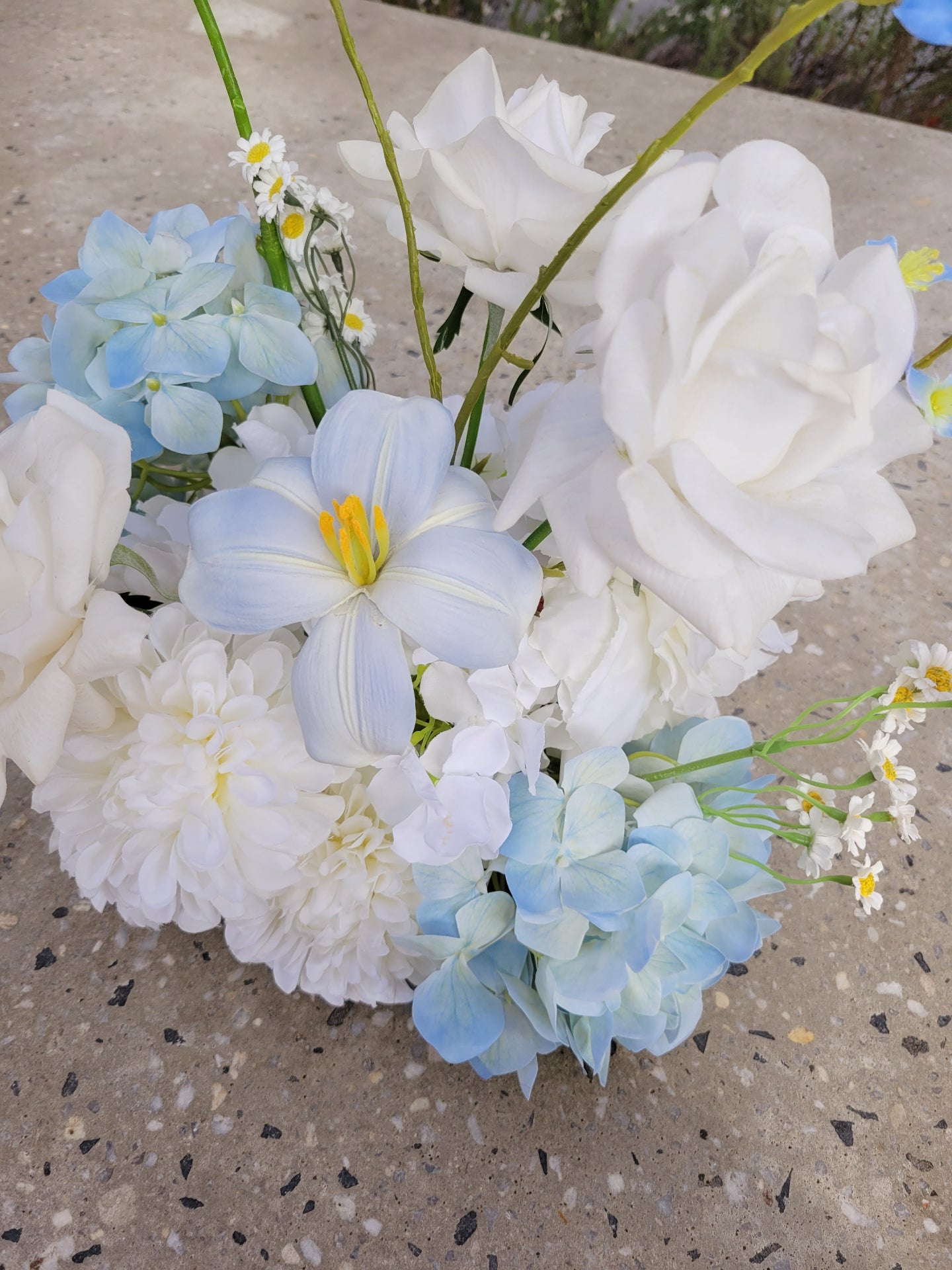Flower cloud of white and light blue flowers on a concrete surface