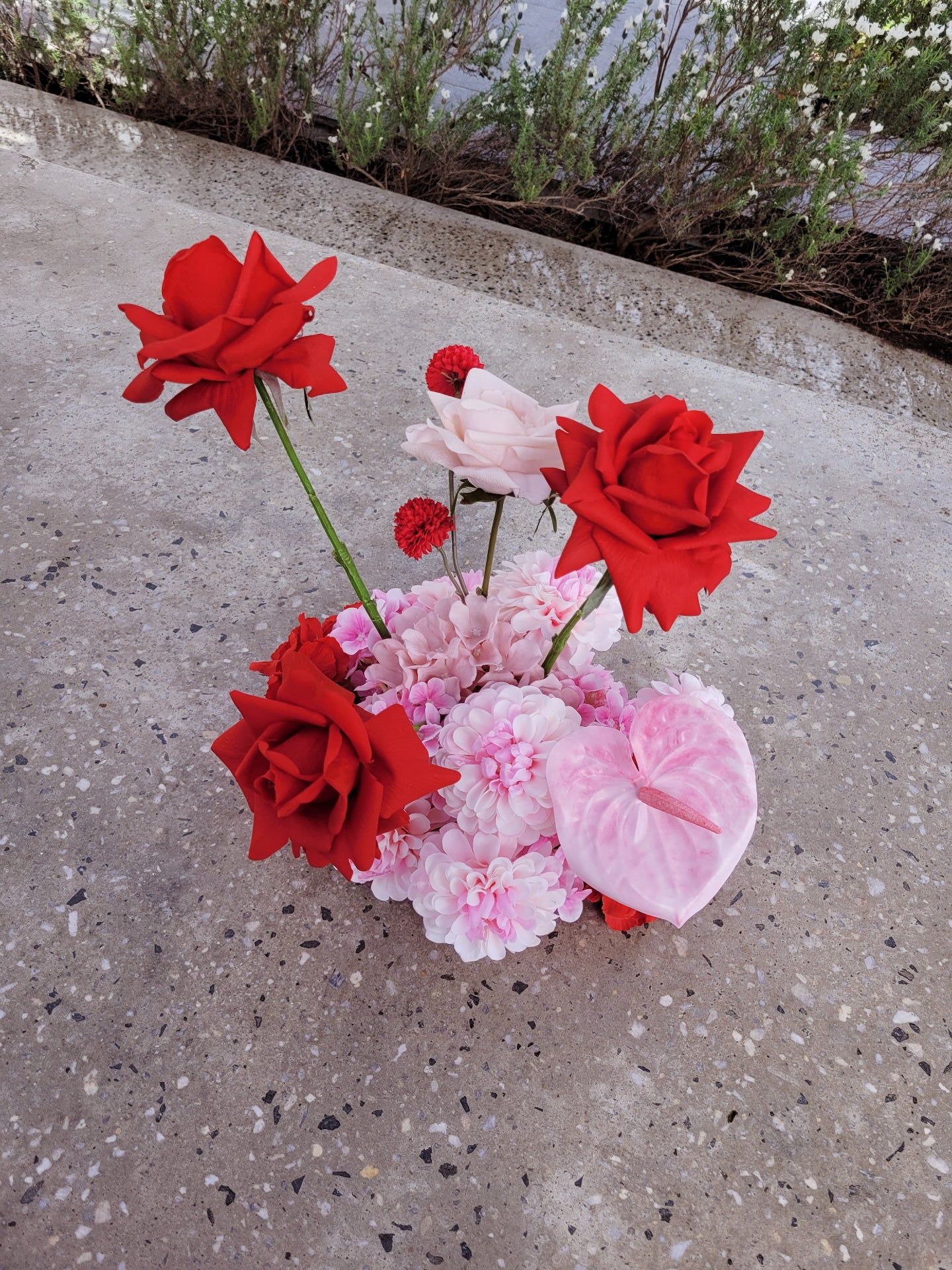 Cloud of red and pink flowers on a concrete surface