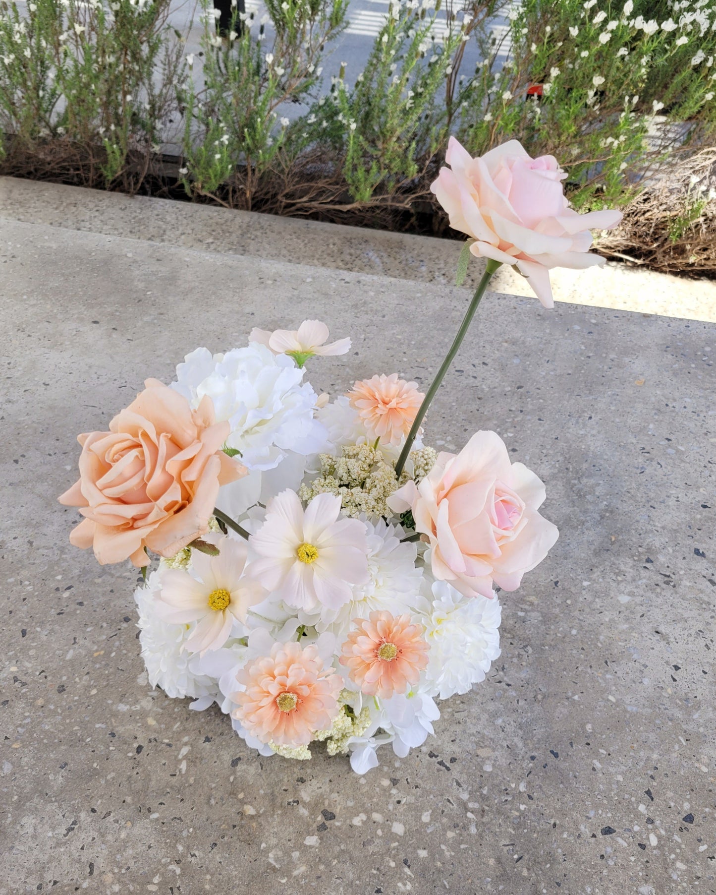 Bouquet of flowers on a concrete surface with greenery in the background
