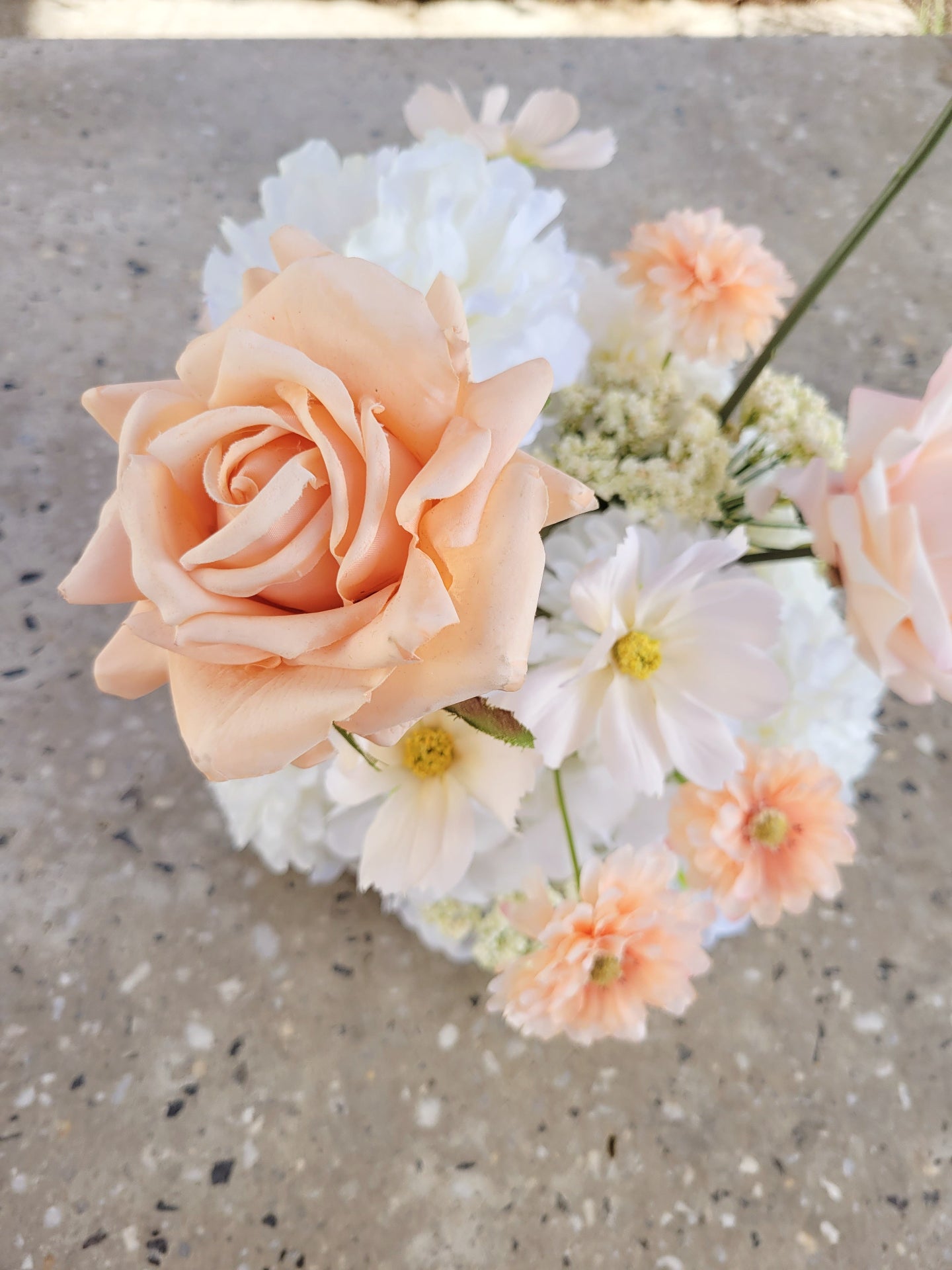 Bouquet of peach and white flowers on a concrete surface