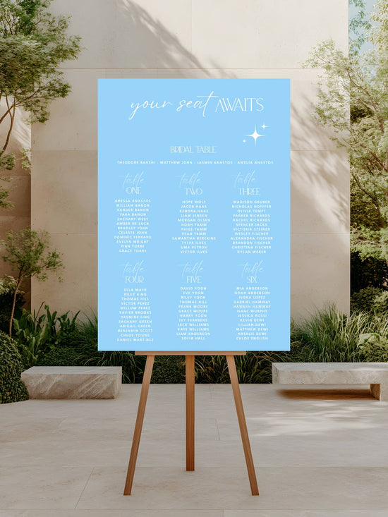 Blue seating chart on an easel outdoors with trees and a building in the background