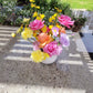 Bright flower arrangement on a concrete bench in a garden setting