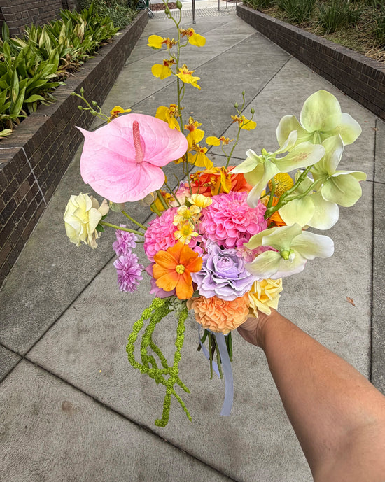 Bouquet of colorful flowers held by a person on a sidewalk