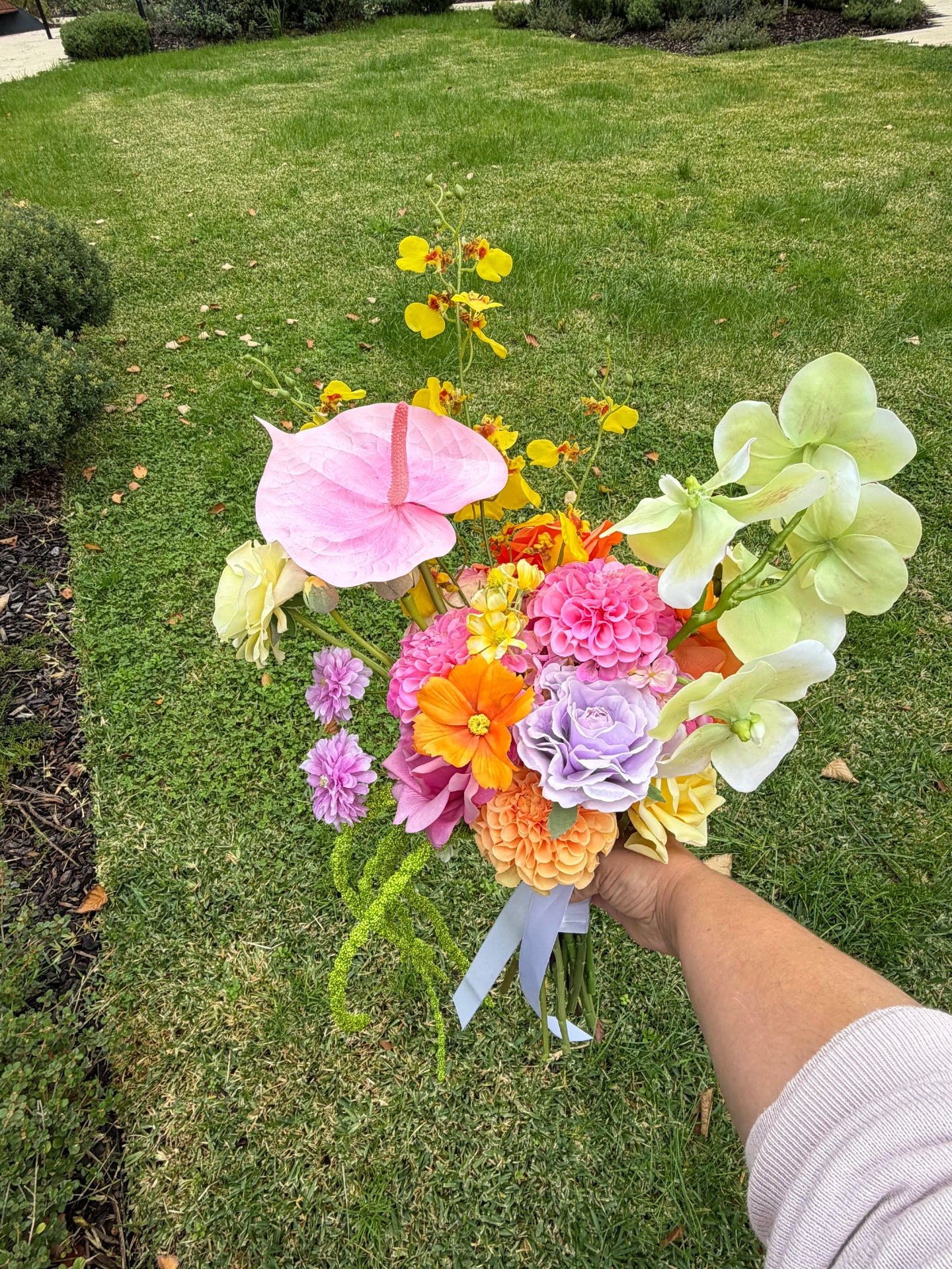 Bouquet of colorful flowers held by a person outdoors on grass