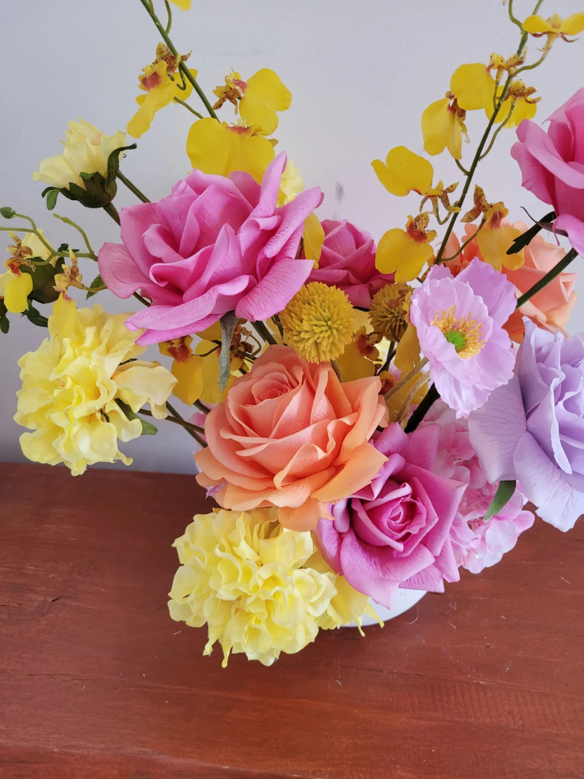 Close up of colourful flowers on a wooden surface with a white background
