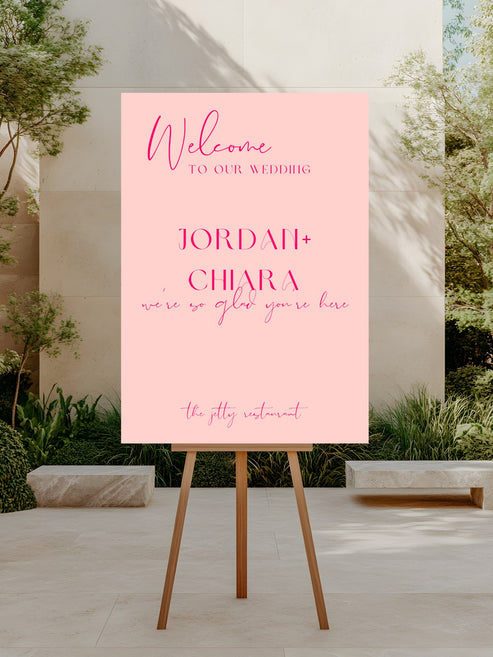 Pink welcome sign for a wedding on an easel outdoors