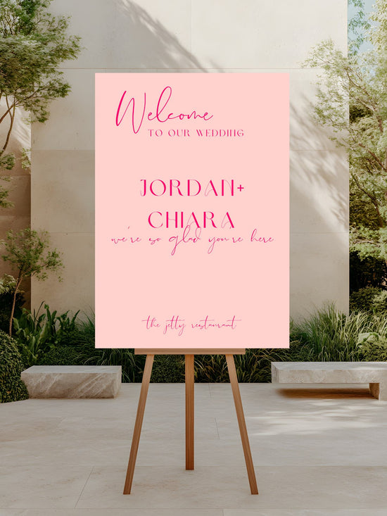 Pink welcome sign for a wedding on an easel outdoors