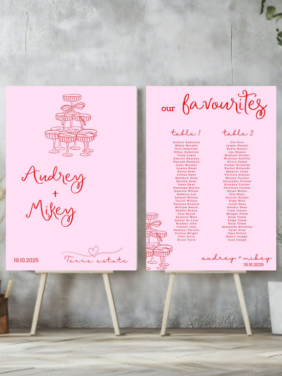 Two pink wedding seating charts on stands against a gray wall.