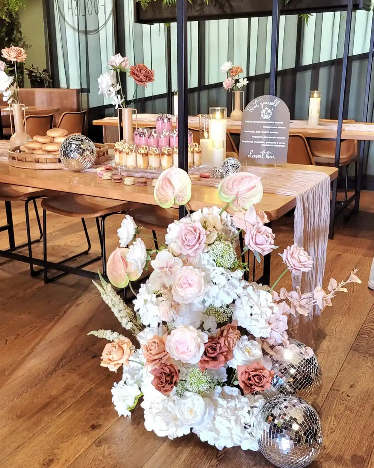 Large floral arrangement sitting beside a dessert table