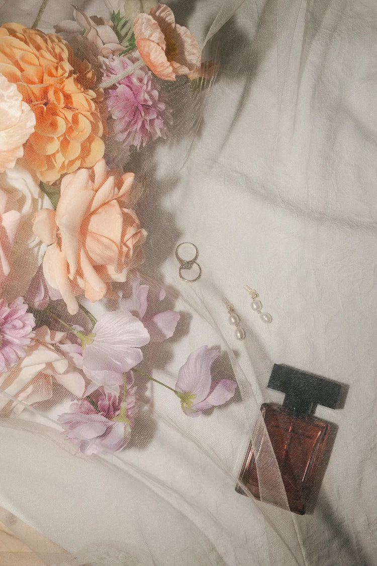 Perfume bottle with flowers and jewelry on a linen surface