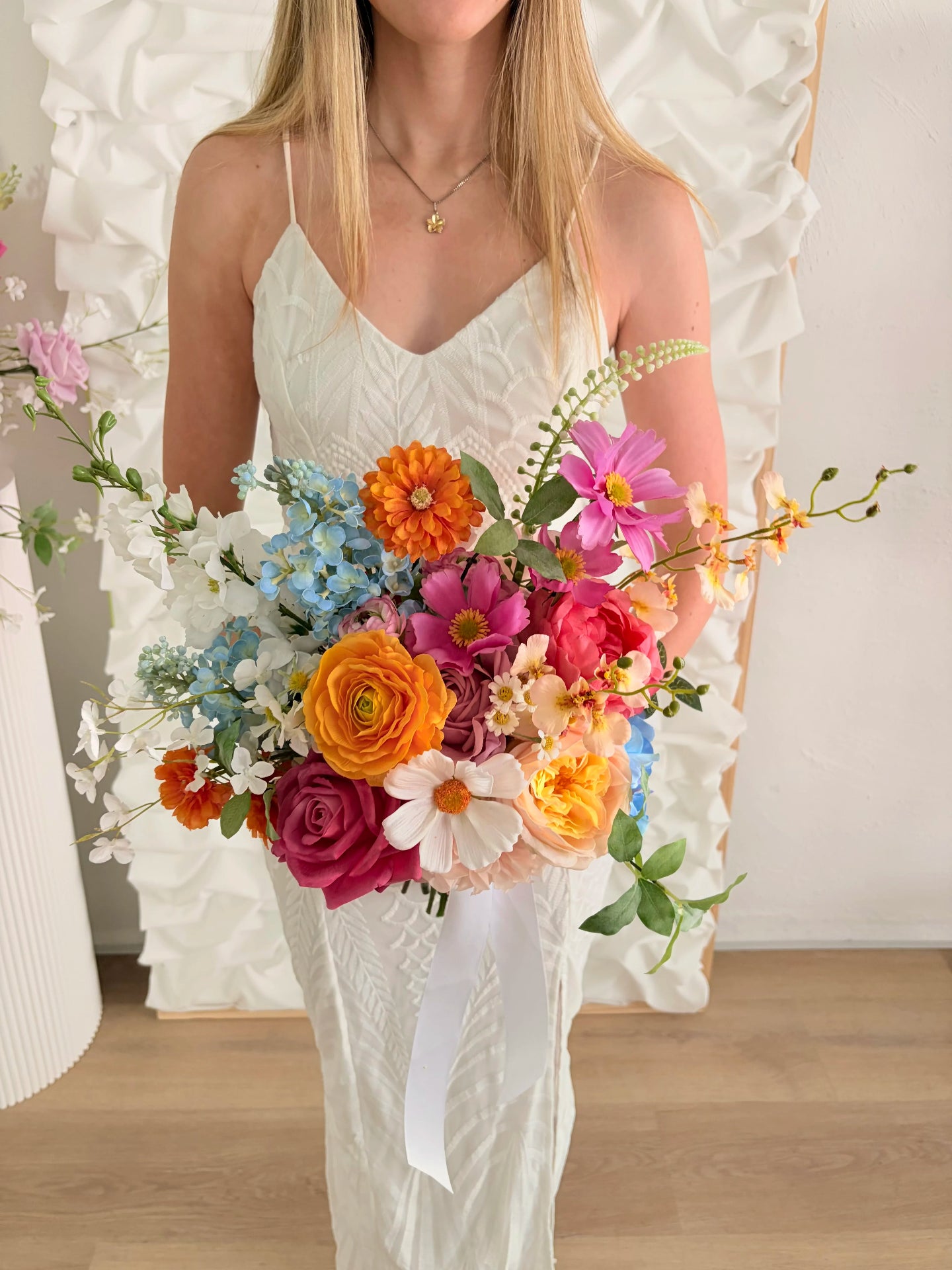 Woman holding a colorful bouquet of faux flowers in a softly blurred indoor setting
