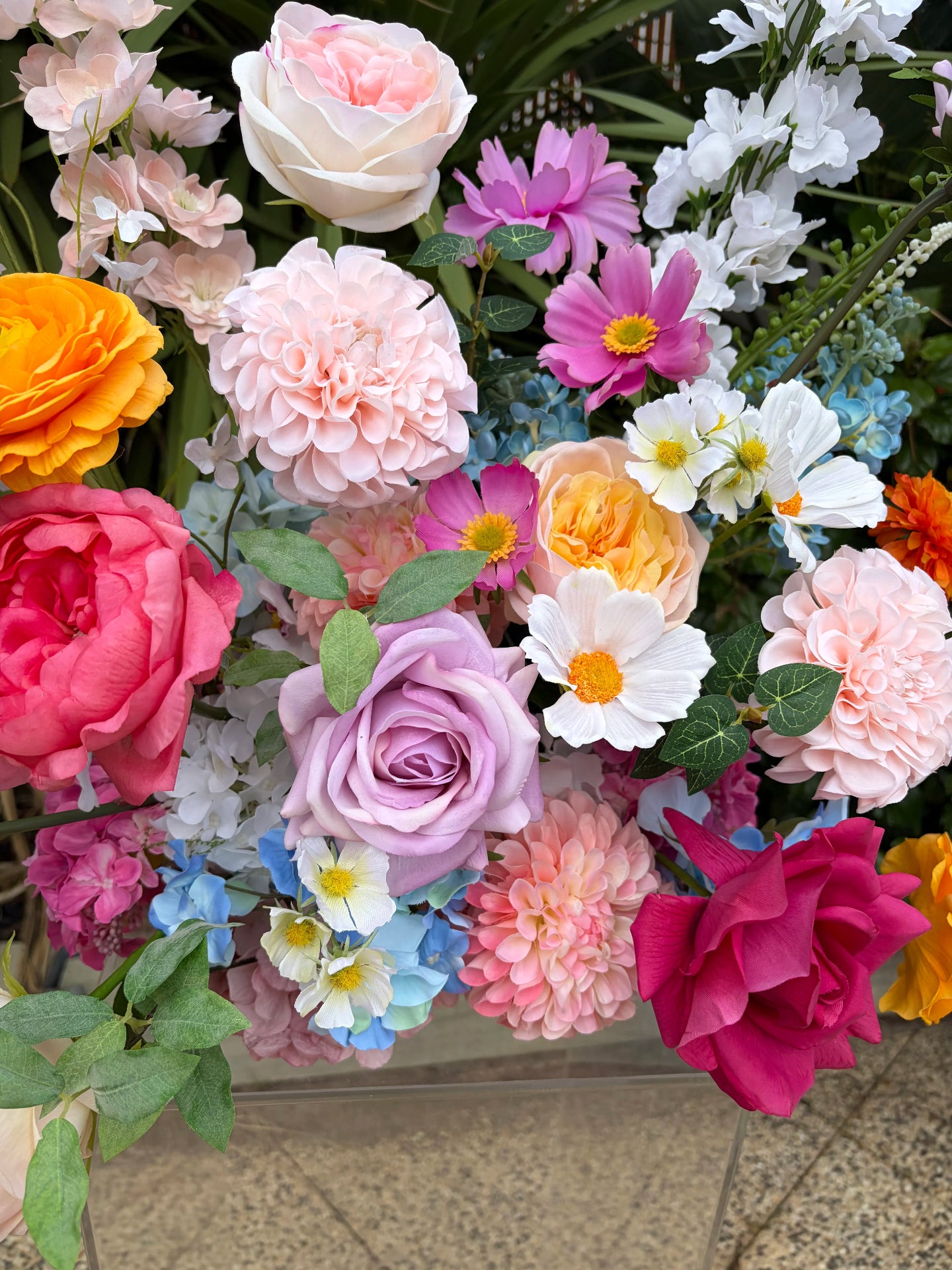 Close up of colourful flowers including roses, dahlias and cosmos in an outdoor setting