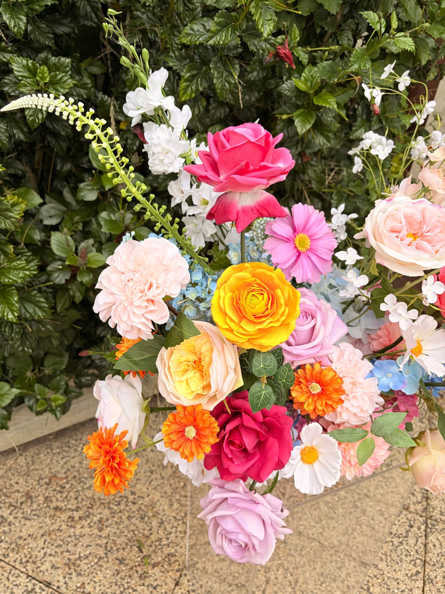 Close up of colourful faux flowers focusing on orange ranunculus and pink roses