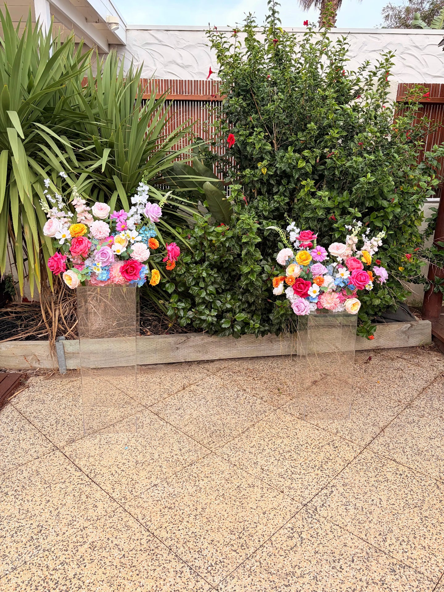 Two artificial flower arrangements for a wedding with greenery in the backgrond