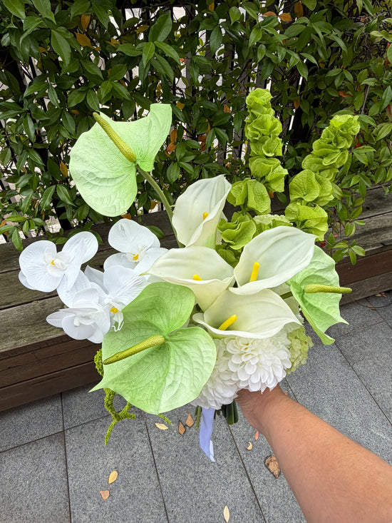 Bouquet of white and green flowers held by a person with a garden background