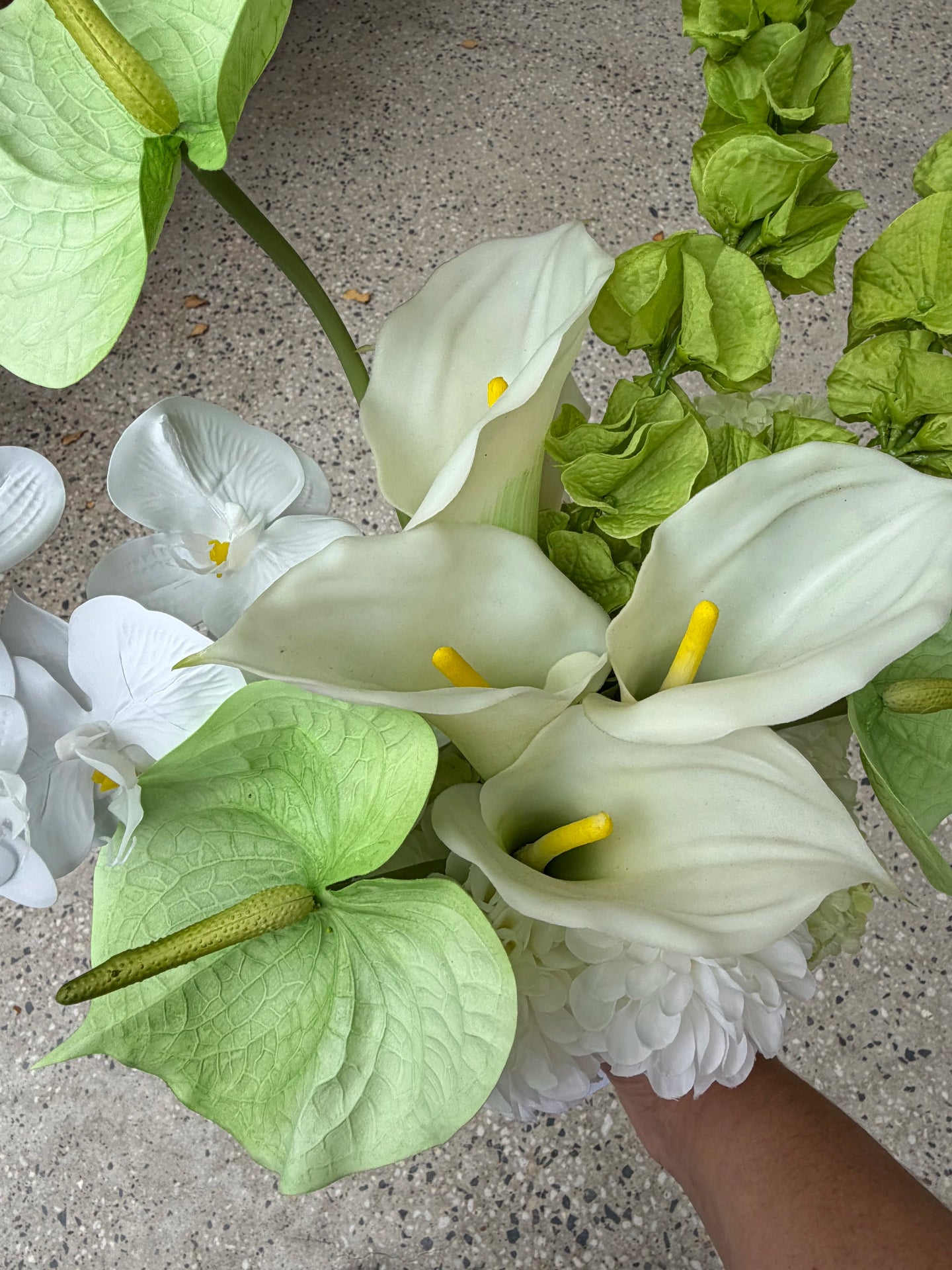 Bouquet of white lilies and green anthuriums on a concrete surface