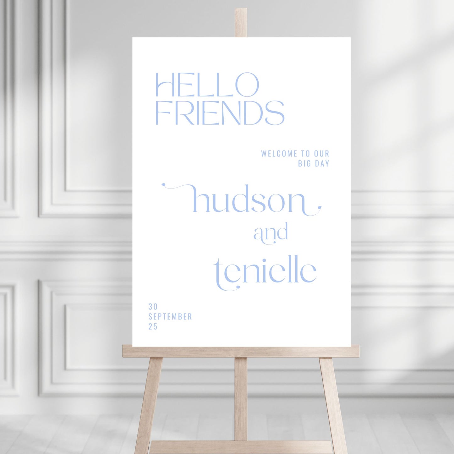 White sign with blue text on a wooden stand against a light gray wall.