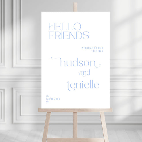 White sign with blue text on a wooden stand against a light gray wall.