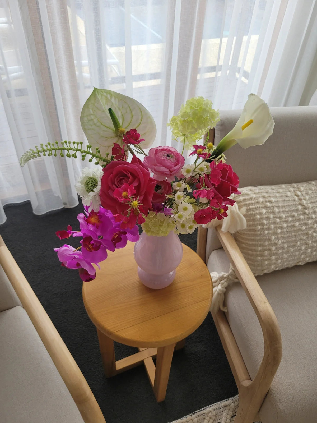Artificial flower arrangement in a purple vase on a wooden coffee table
