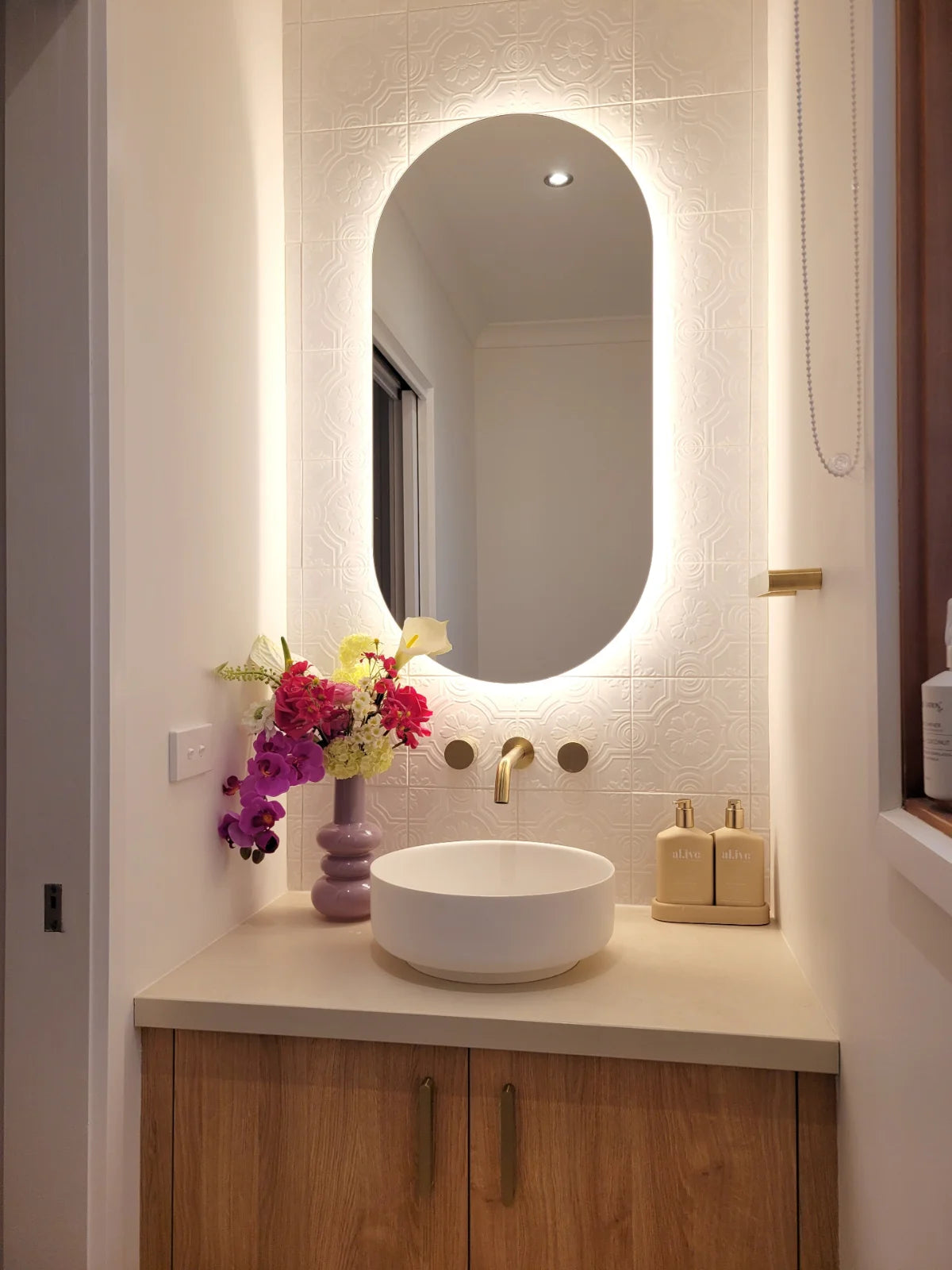 Bathroom vanity with illuminated mirror, sink, and decorative elements.