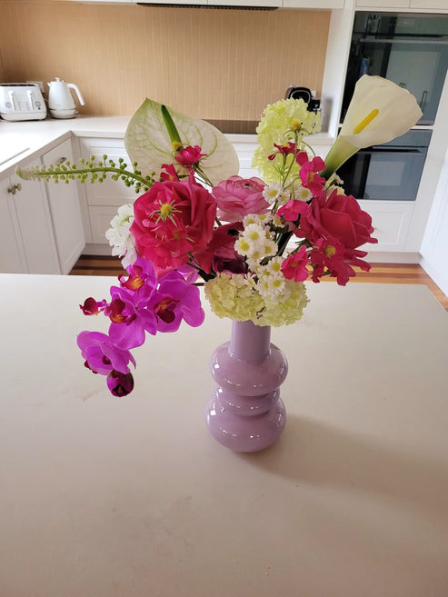 Flower arrangement is a purple vase featuring a calla lily and orchid