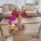 Living room with a coffee table featuring a vase of artificial flowers and magazines.