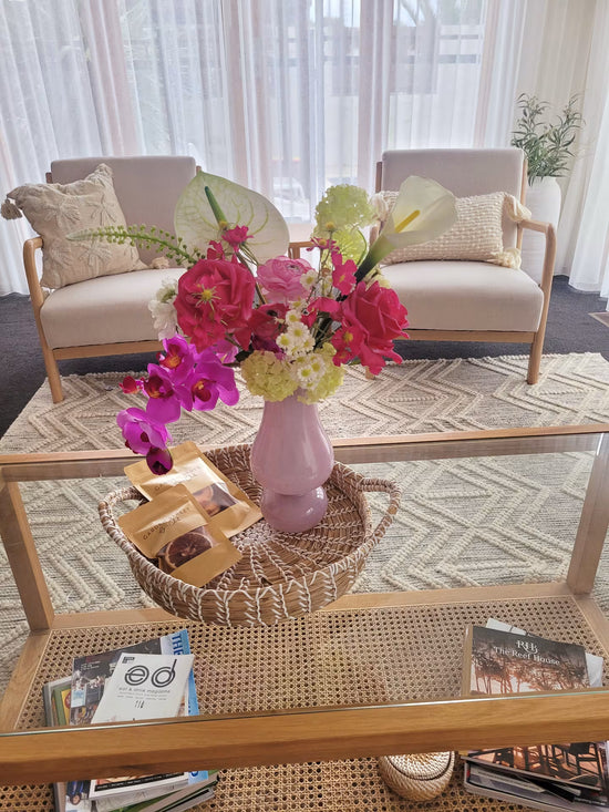 Living room with a coffee table featuring a vase of artificial flowers and magazines.