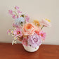 Pastel faux flower arrangement with peach, lilac, blue and pink tones