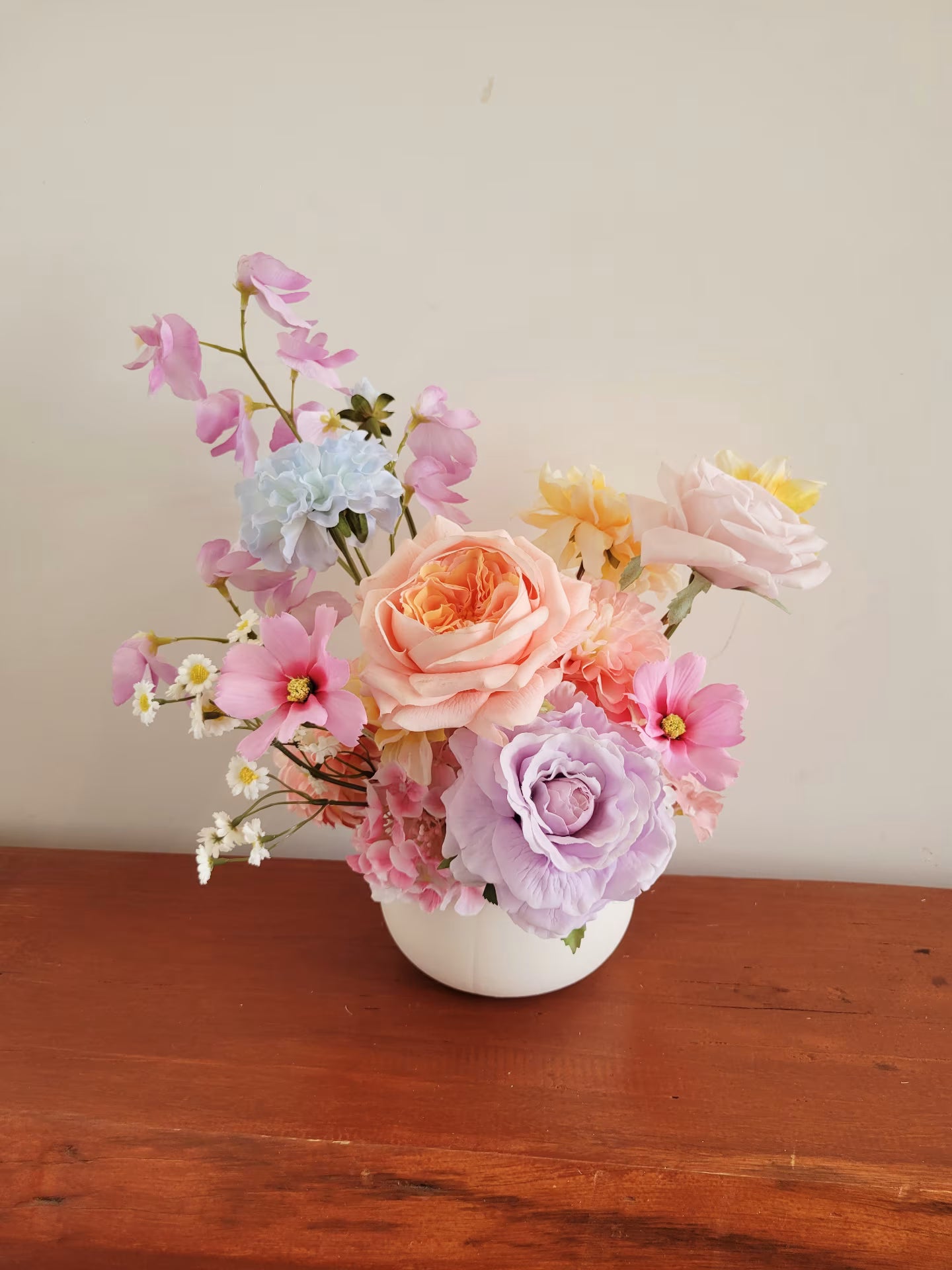 Pastel faux flower arrangement with peach, lilac, blue and pink tones