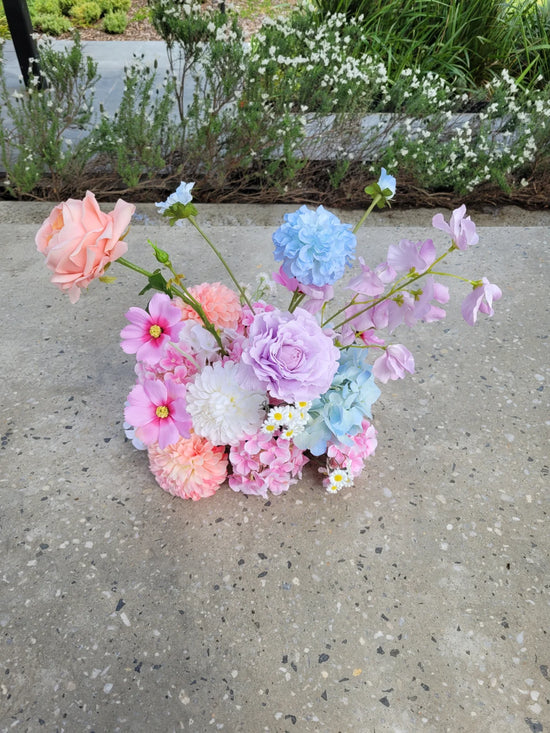 Pastel-coloured flower cloud on a concrete surface with greenery in the background