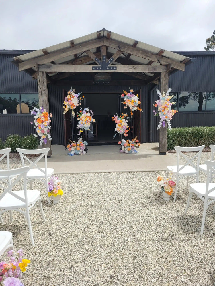 Wedding hall adorned with multiple colourful floral arrangements for a ceremony