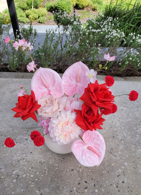 Flower arrangement of red and pink flowers on a concrete bench